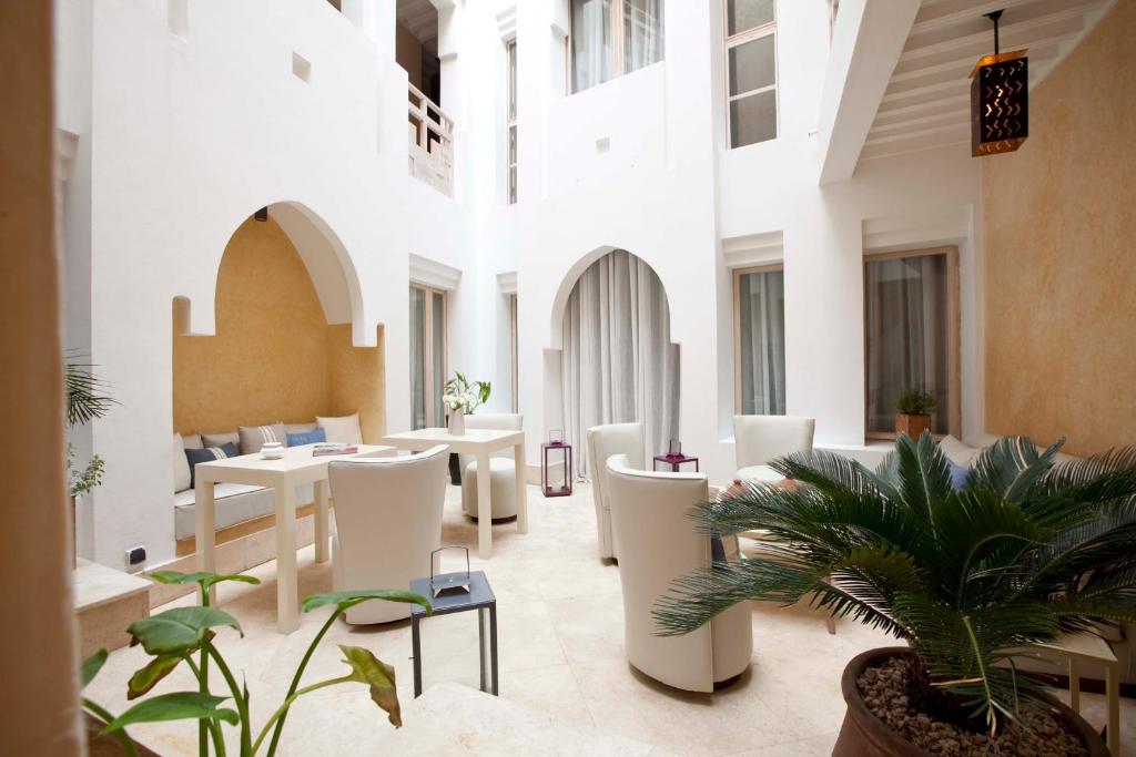 a lobby with tables and chairs and plants at Riad Dar Maya in Essaouira