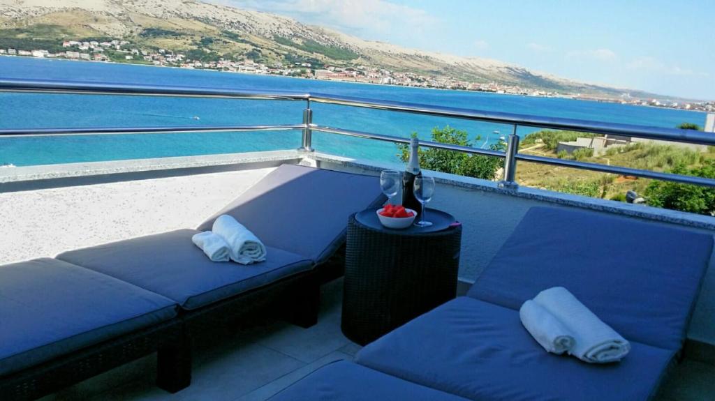 einen Balkon mit zwei blauen Sofas und Blick auf das Wasser in der Unterkunft Solaria apartments in Pag