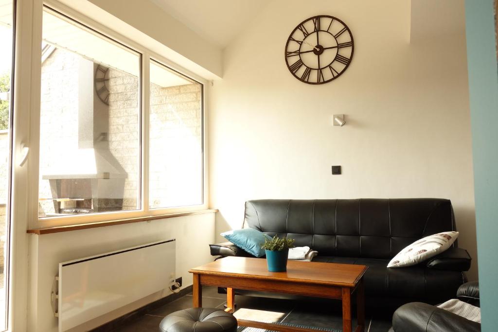 a living room with a black leather couch and a clock at Belle vue in Malmedy