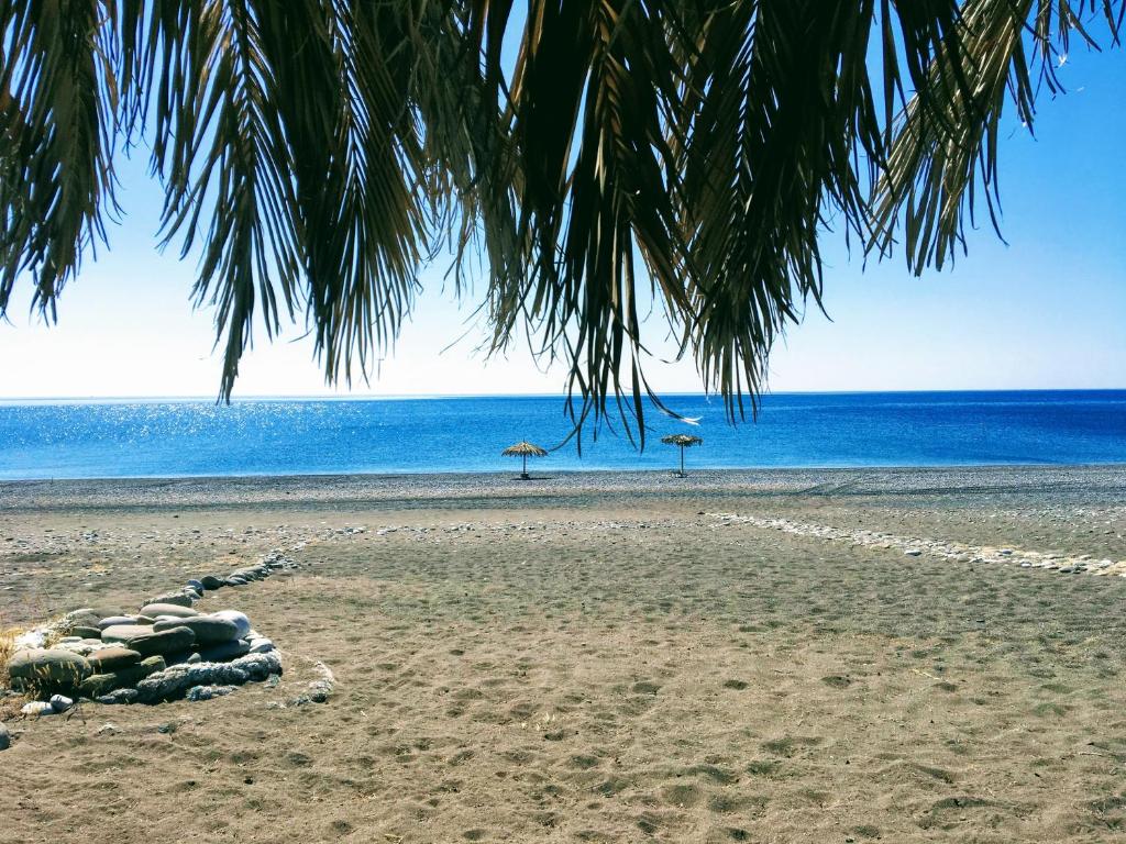 a beach with some umbrellas and the ocean at Ktima Tzaneti in Lachania