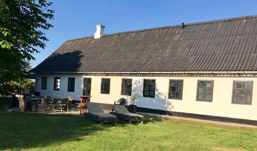 a white house with a black roof and some chairs at 7 Bedrooms Horse Farm near Skagen in Jerup