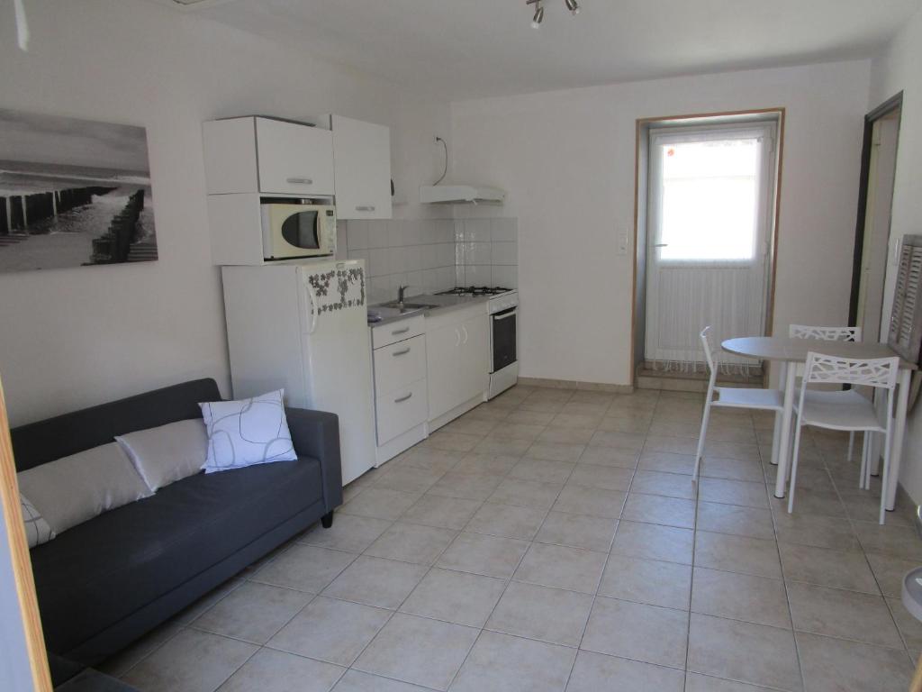 a kitchen and living room with a couch and a table at maisonnette avec jardin proche du Mont Saint Michel in Pontorson
