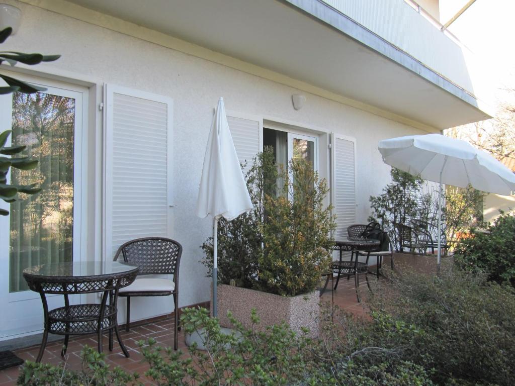un patio con mesas, sillas y una sombrilla en Casa Sandra, en Locarno