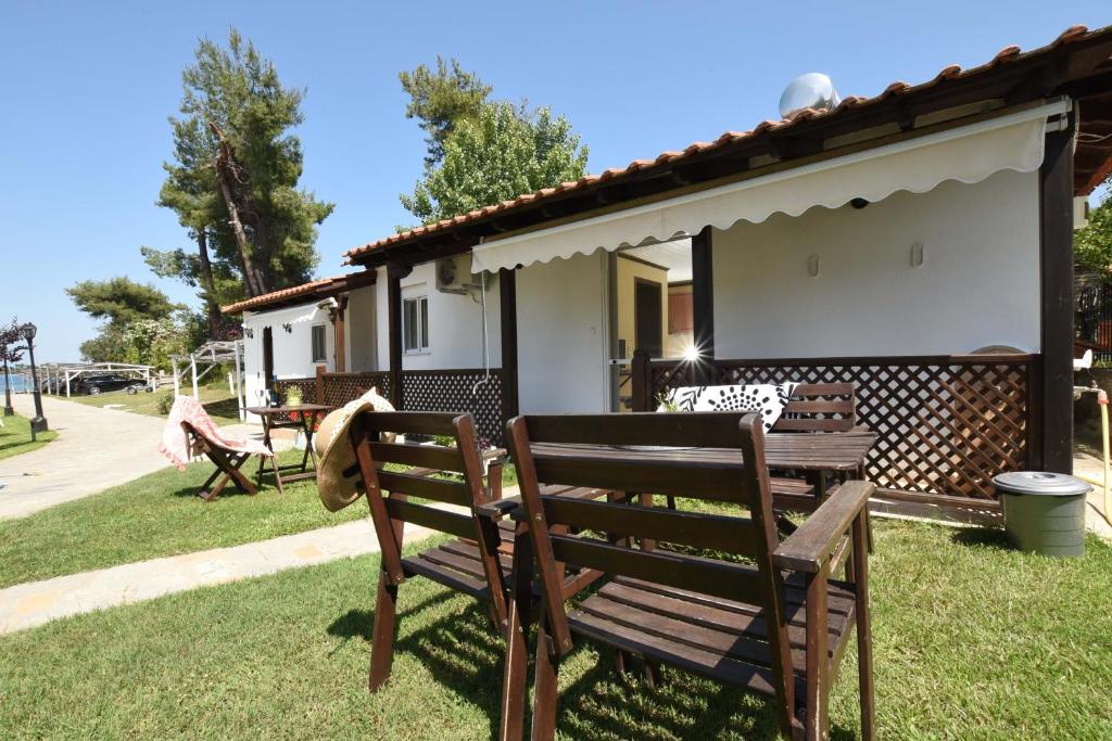 a house with two wooden chairs in the yard at Haus Platanos Apartments & Bungalows by the Sea in Vourvourou