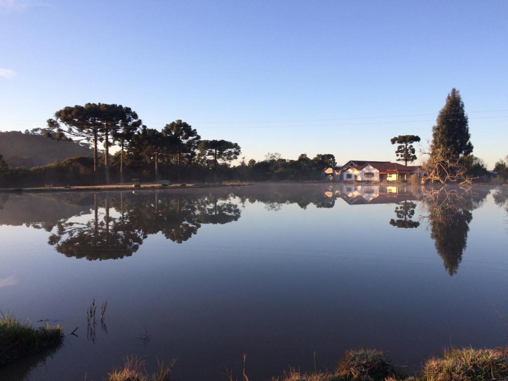 a misty lake with a house in the background at Sítio Rota das Araucárias in Urupema