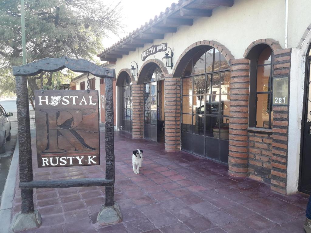 een hond die voor een bakstenen gebouw staat bij Hostal Rustyk in Cafayate