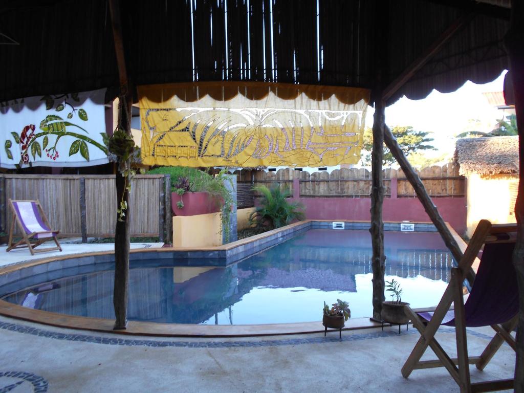 a swimming pool with a chair and a umbrella at Hotel Ambalamanga in Nosy Be