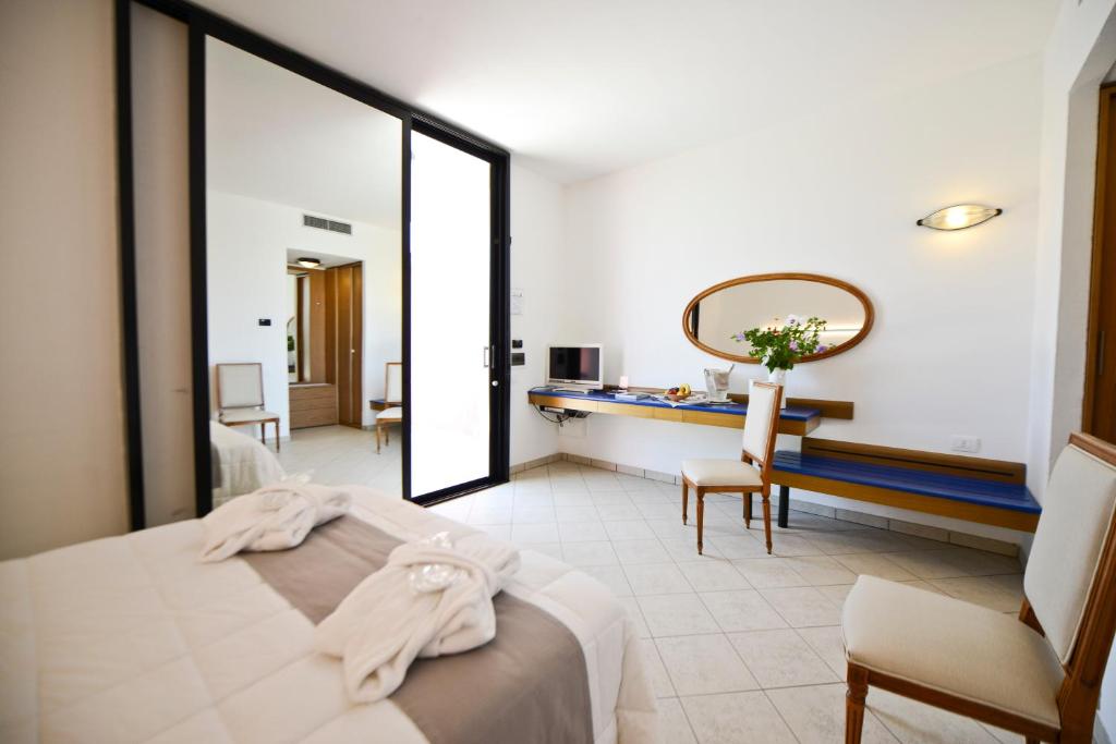 a bedroom with a bed and a desk and a mirror at Grand Hotel Masseria Santa Lucia in Ostuni
