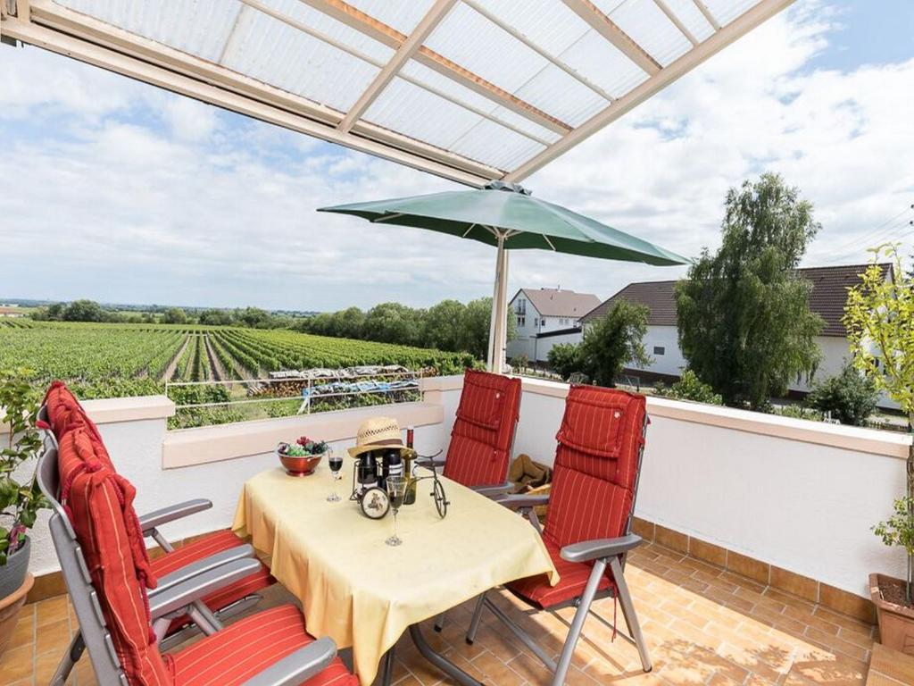 a patio with a table and two chairs and an umbrella at Ferienwohnung Rebenmeer in Neustadt an der Weinstraße
