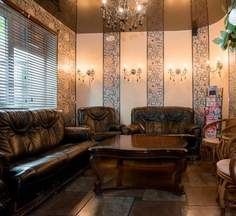 a living room with leather furniture and a chandelier at Hotel Incanto in Vladivostok