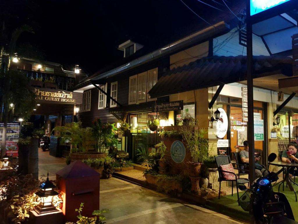 een groep mensen die 's nachts buiten een gebouw zitten bij Baanfai Guesthouse Chiangkhong in Chiang Khong