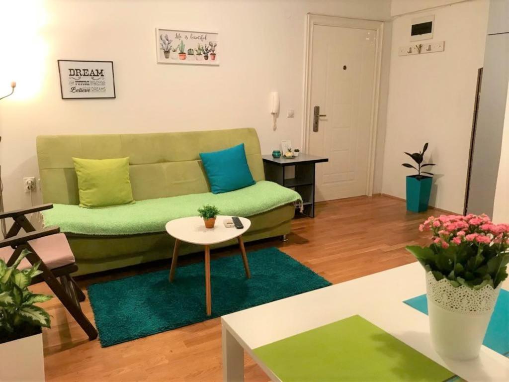sala de estar con sofá verde y mesa en Regina's Park Studio Apartment, en Skopje