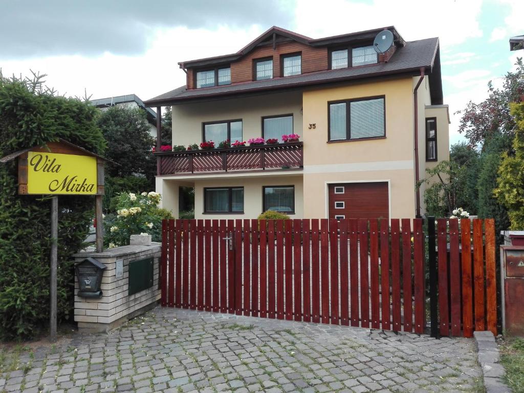 a house with a red fence and a sign at Vila Mirka in Poprad