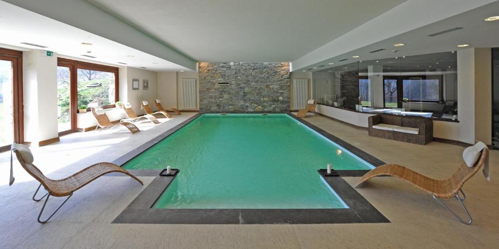 a large swimming pool with chairs and a stone wall at Maison Tissiere in Antey-Saint-André