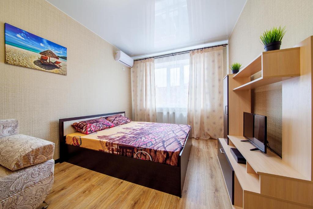 クラスノダールにあるЖК ПАНОРАМА 30のベッド1台とテレビが備わる小さな客室です。