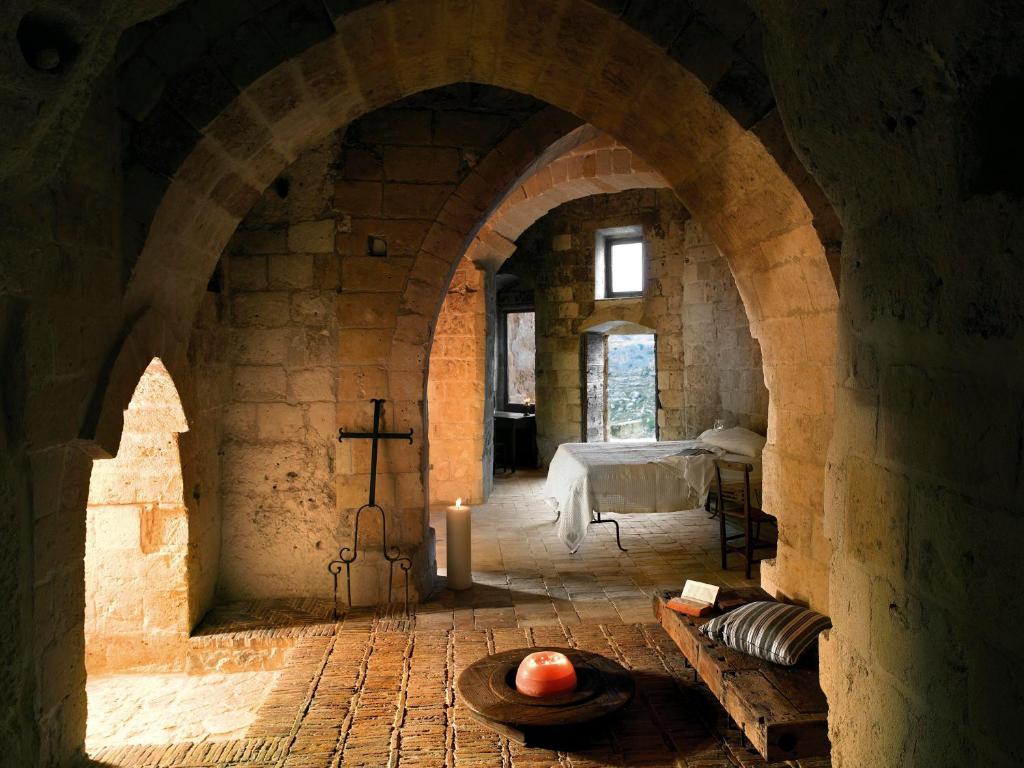 a room with an archway with a table and a bed at Sextantio Le Grotte Della Civita in Matera