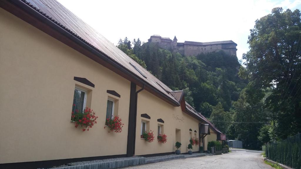 een gebouw met bloembakken en een kasteel op de achtergrond bij Penzión U nás in Oravský Podzámok