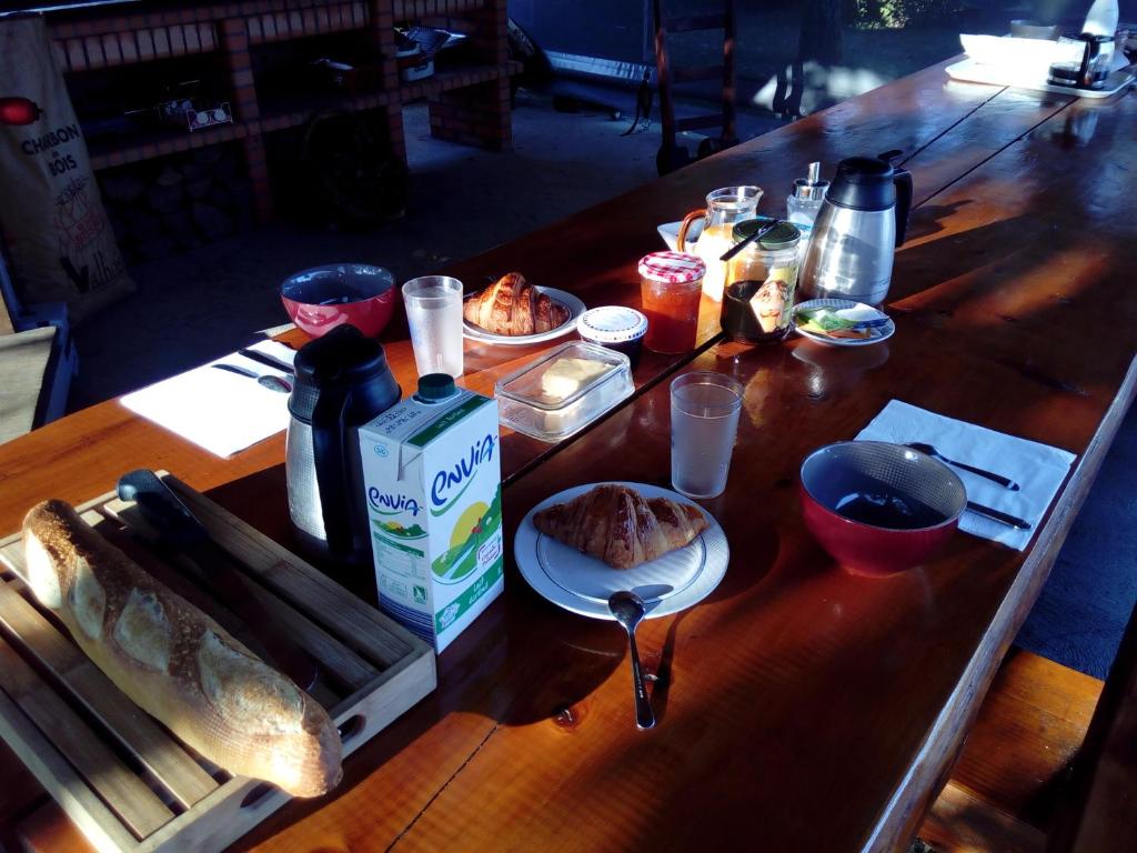 una mesa de madera con comida y bebidas. en Chambre d'hotes des Poisets, en Crotenay