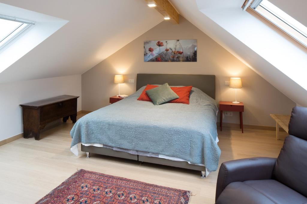 ein Schlafzimmer mit einem Bett und einem Sofa im Dachgeschoss in der Unterkunft Barbara's Bed & Breakfast in Sterrebeek