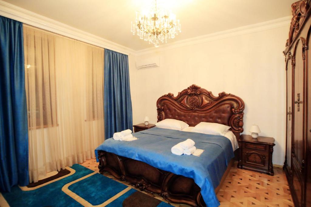 a bedroom with a bed with blue sheets and a chandelier at Old District in Kutaisi