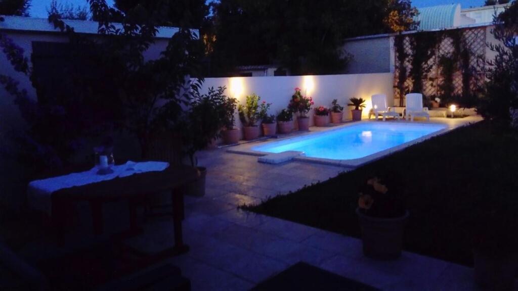 - une piscine dans un jardin la nuit dans l'établissement L'Hibiscus Chambre d'Hôte, à Avignon