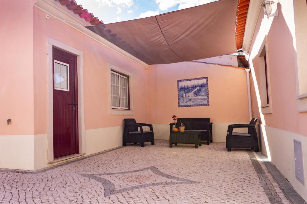 un patio con sillas y toldo en una casa en A Casa da Avó Ana en Arneiro das Milhariças