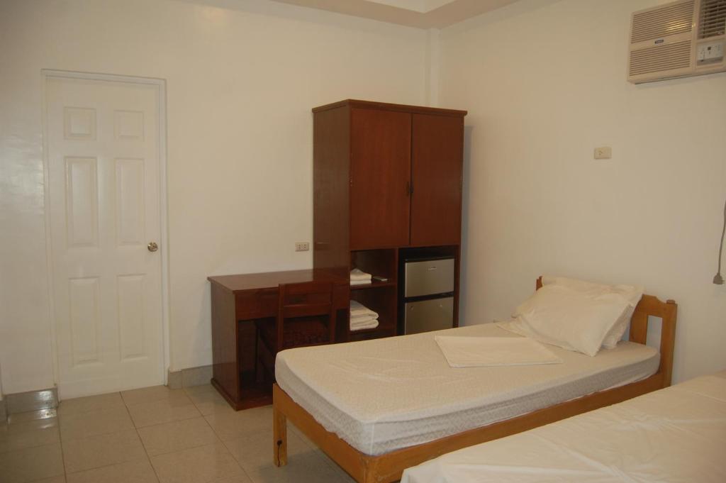 a bedroom with two beds and a cabinet and a door at CafeMare Rooms in Bantayan Island