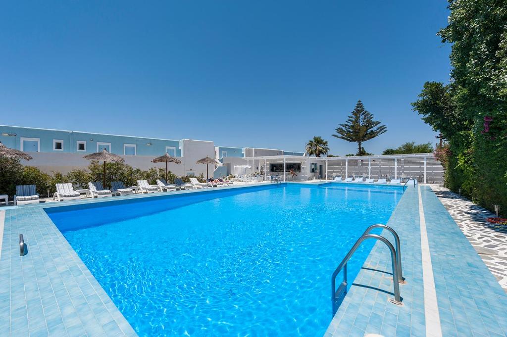 a large blue swimming pool with chairs and a building at Narges Hotel in Aliki