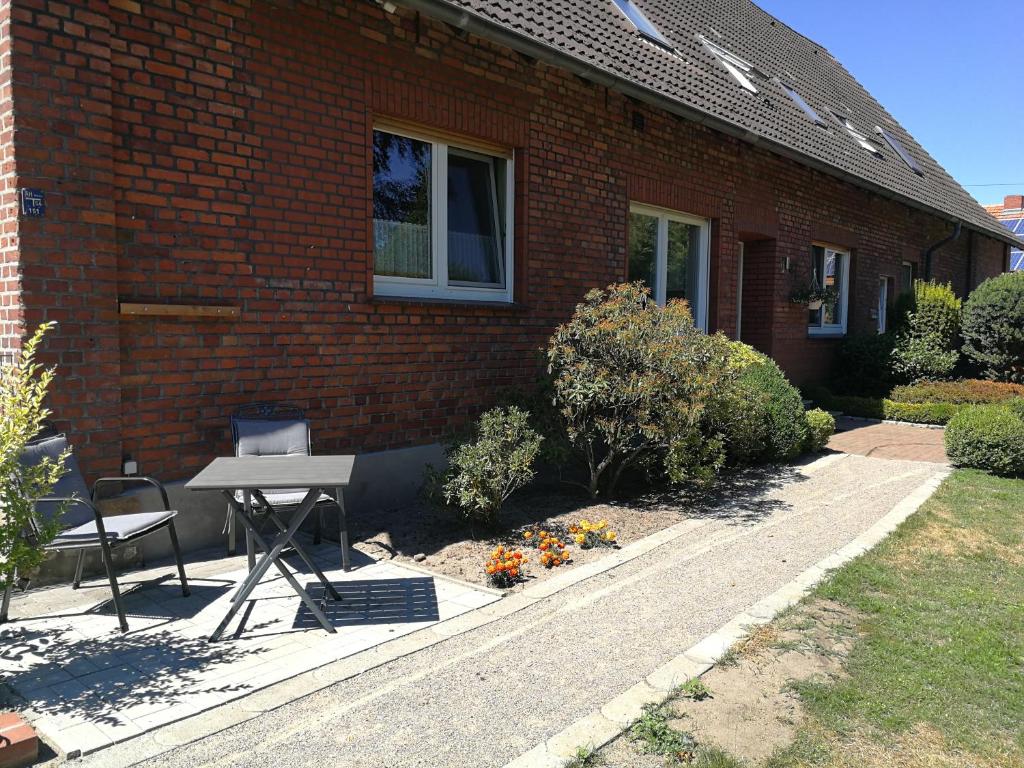 una mesa y una silla frente a una casa de ladrillo en Ferienwohnung Gravemeier, en Ladbergen