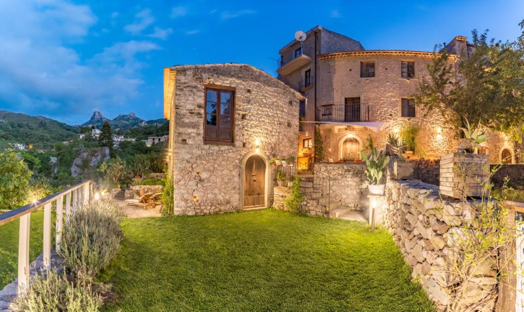 ein altes Steinhaus mit einem grünen Hof in der Unterkunft Old Noar Private Villa in Novara Sicilia
