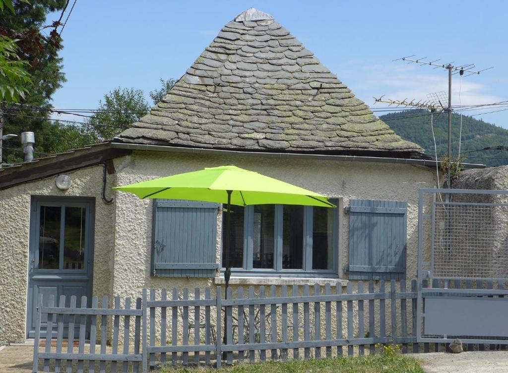 un parasol vert devant une maison dans l'établissement La P'tite Maison, à Saint-Hostien