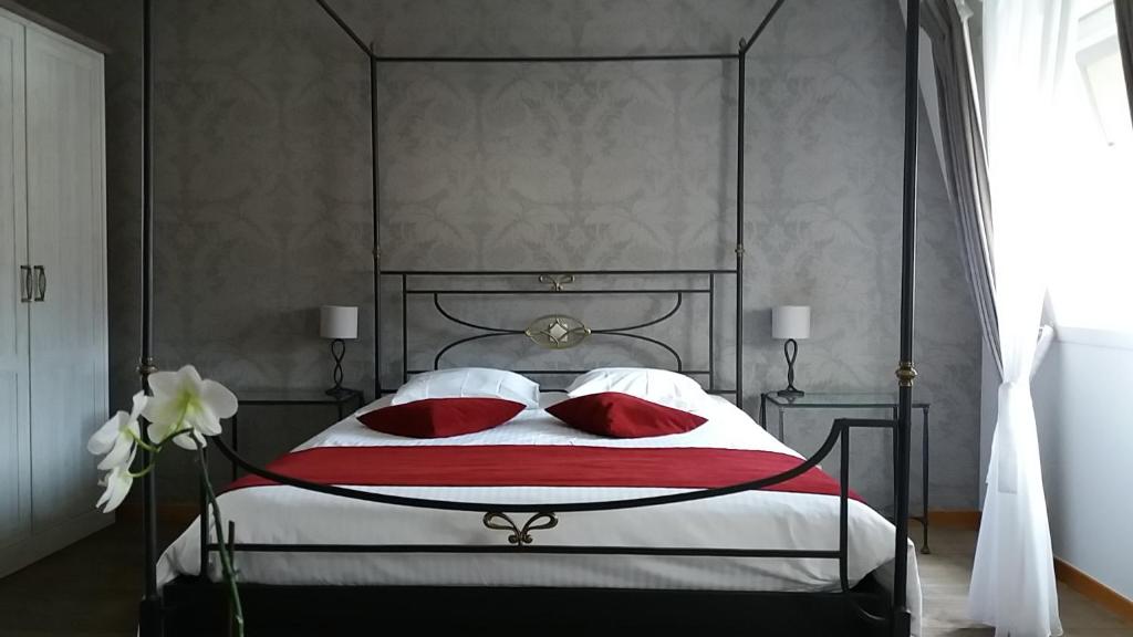 a bedroom with a large bed with red pillows at B&B Villa Des Raisins in Bruges