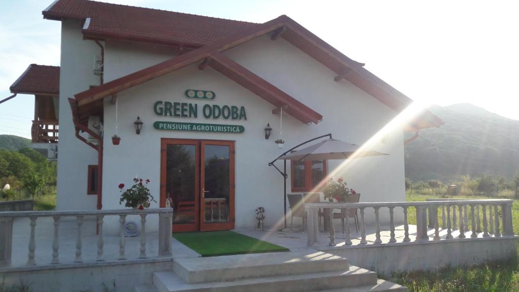 a white building with a green onion restaurant at Pensiunea Agroturistica Green Odoba in Sătuc