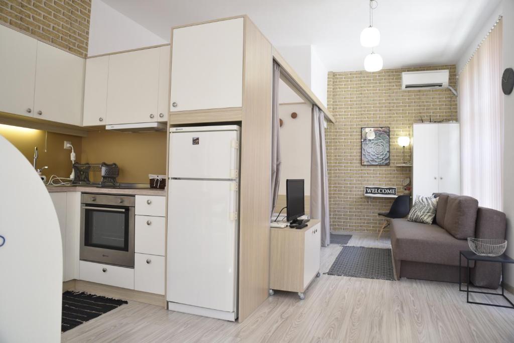 a kitchen with white cabinets and a living room at Studio Toni in Sliven
