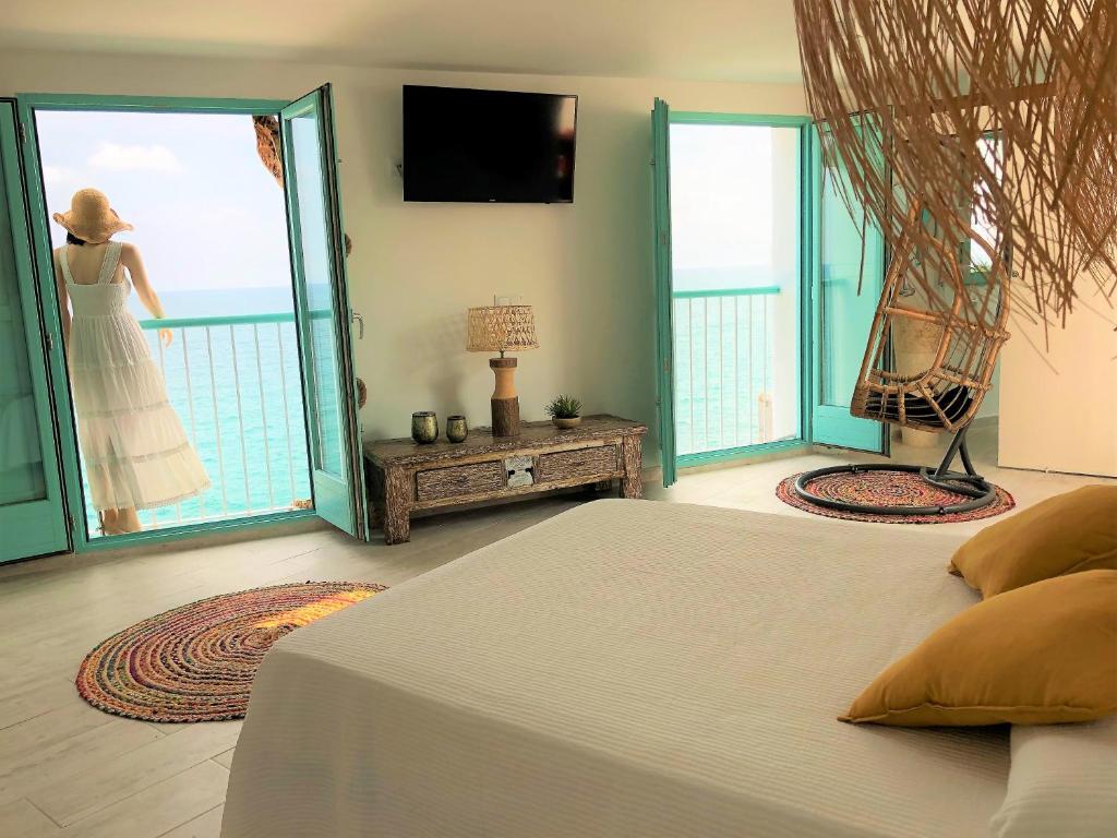 Un dormitorio con una cama y una mujer de pie en un balcón en Respirar, en Peñíscola