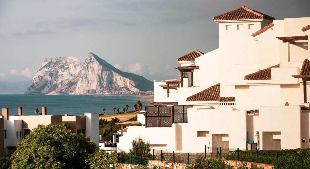 a white building with a mountain in the background at Golf Beach and Relax Townhouse in La Alcaidesa