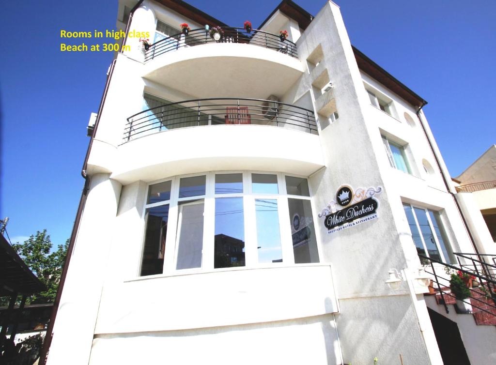 ein weißes Gebäude mit Balkon darüber in der Unterkunft Boutique Vila White Duchess in Mamaia Nord – Năvodari