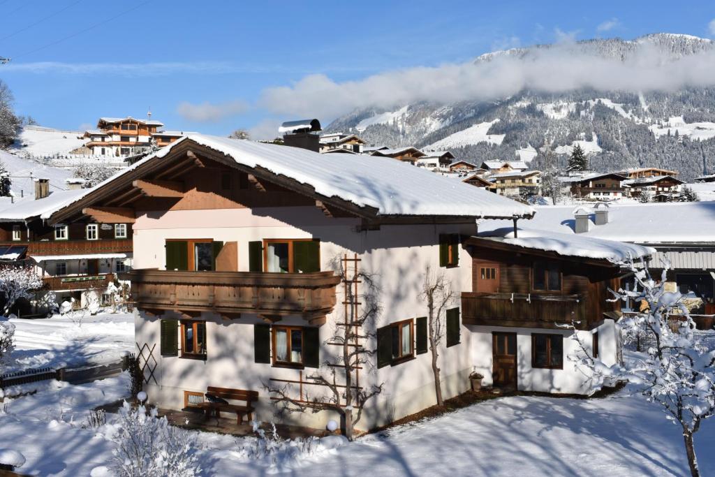 a house covered in snow with a mountain in the background at Ferienhaus am Gebraweg in Fieberbrunn in Tirol - Saalbach, Leogang, Hochfilzen, Kitzbühel in Fieberbrunn