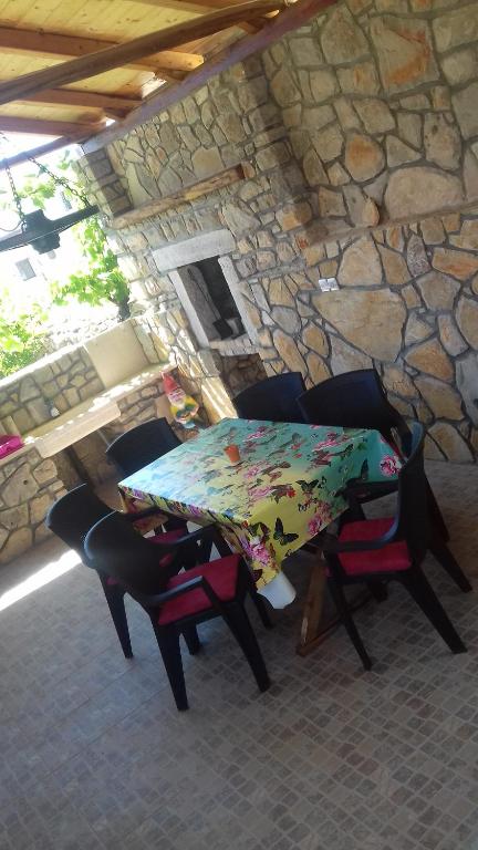 una mesa y sillas frente a una pared de piedra en HOLIDAY HOME NORA**** Loznati Cres, en Loznati