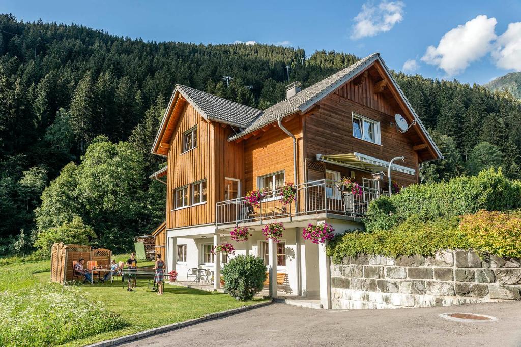 une maison sur une colline avec des personnes assises à l'extérieur dans l'établissement Haus Ambiatscha, à Sankt Gallenkirch