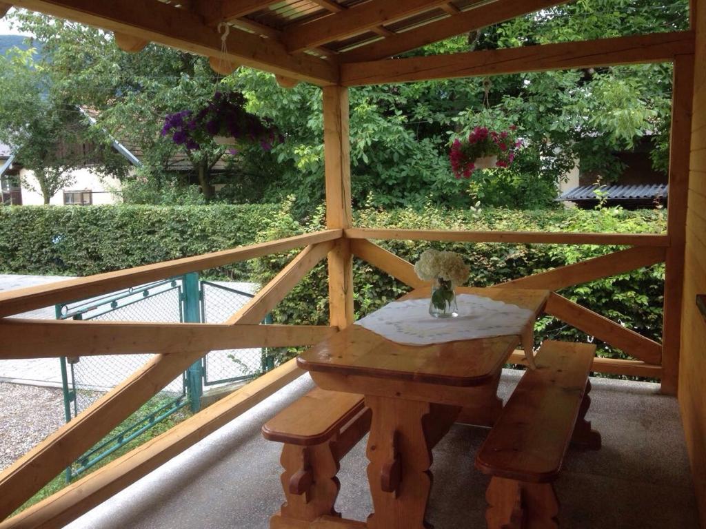 een houten tafel en bank op een afgeschermde veranda bij Садиба "Сонячна" in Kosiv