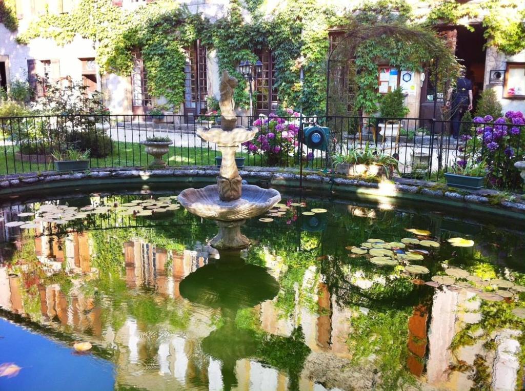 une fontaine au milieu d'un étang avec des nénuphars dans l'établissement Hostellerie Du Grand Duc, à Gincla