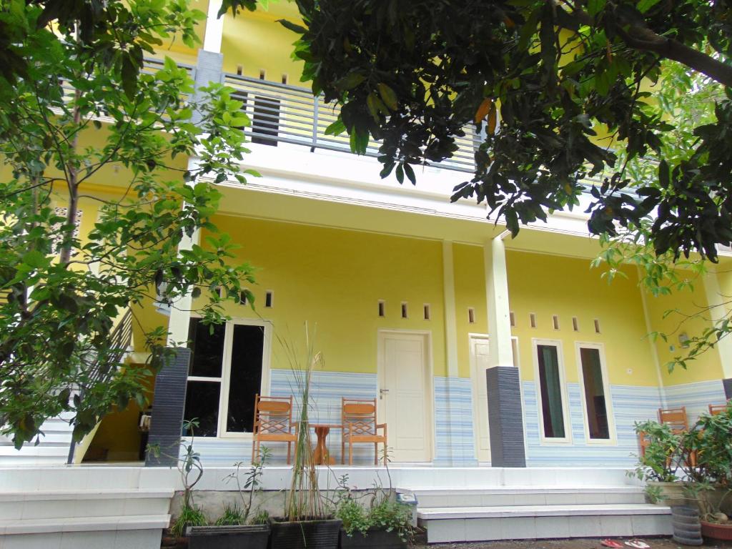 een geel en blauw huis met stoelen op de veranda bij ZONA Homestay in Selong