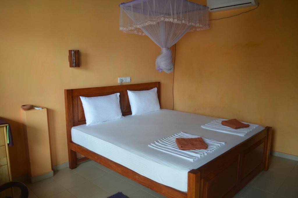 1 dormitorio con 1 cama con sábanas blancas y almohadas blancas en Hotel Paradiso, en Hikkaduwa