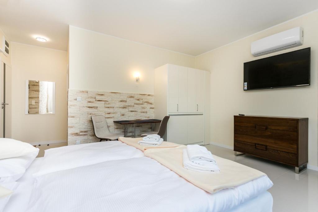 1 dormitorio con 1 cama blanca y TV en la pared en Apartamenty Dom Saski 10 minut od Centrum Warszawy en Varsovia
