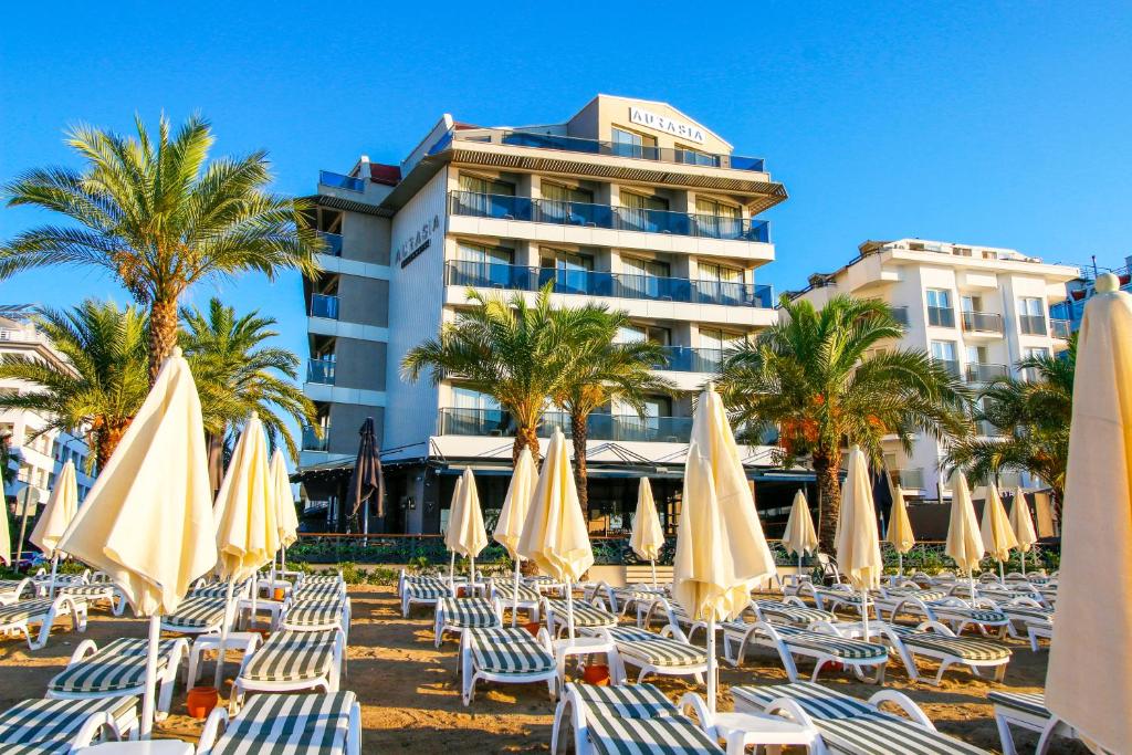 a group of chairs and umbrellas in front of a hotel at Aurasia Beach Hotel in Marmaris