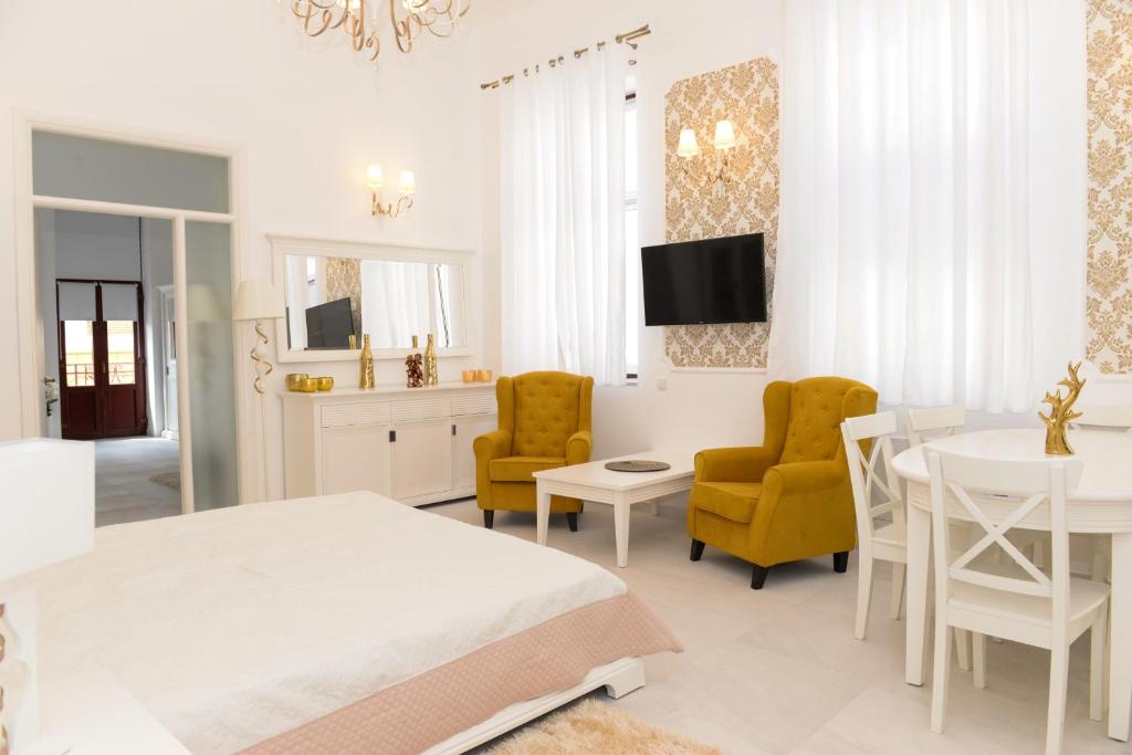 a white bedroom with a bed and a table and chairs at Modern Central-Near Unirii Square in Cluj-Napoca