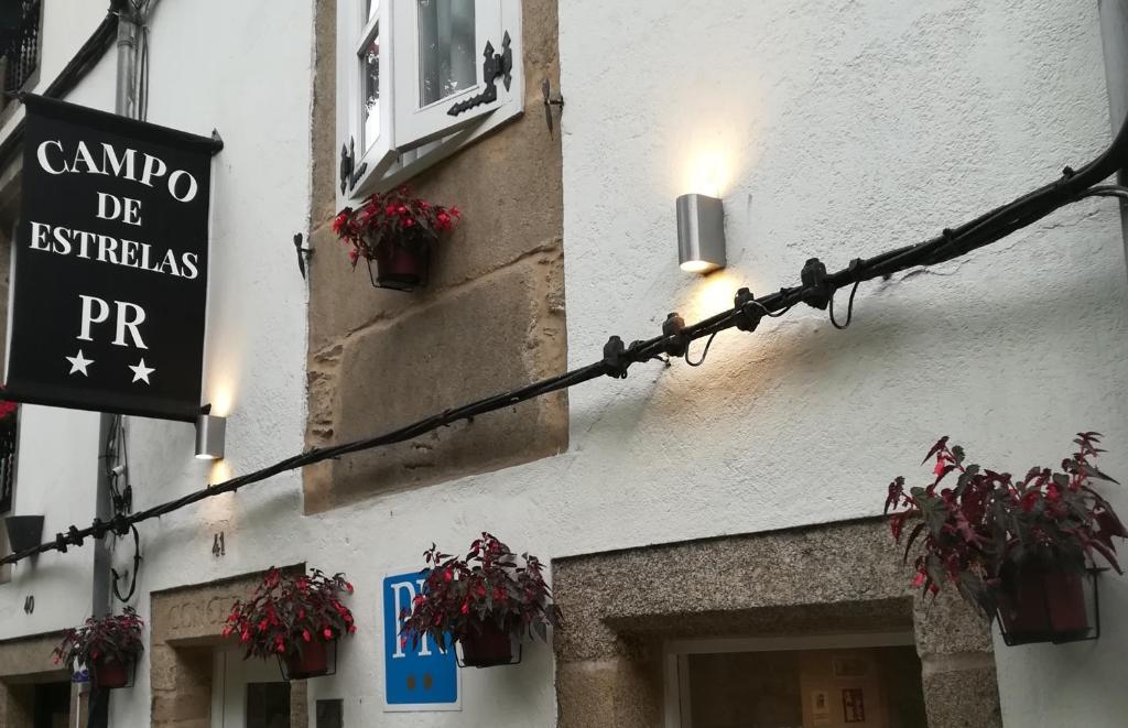 un letrero de la calle al lado de un edificio con plantas en Hostal Campo de Estrelas, en Santiago de Compostela