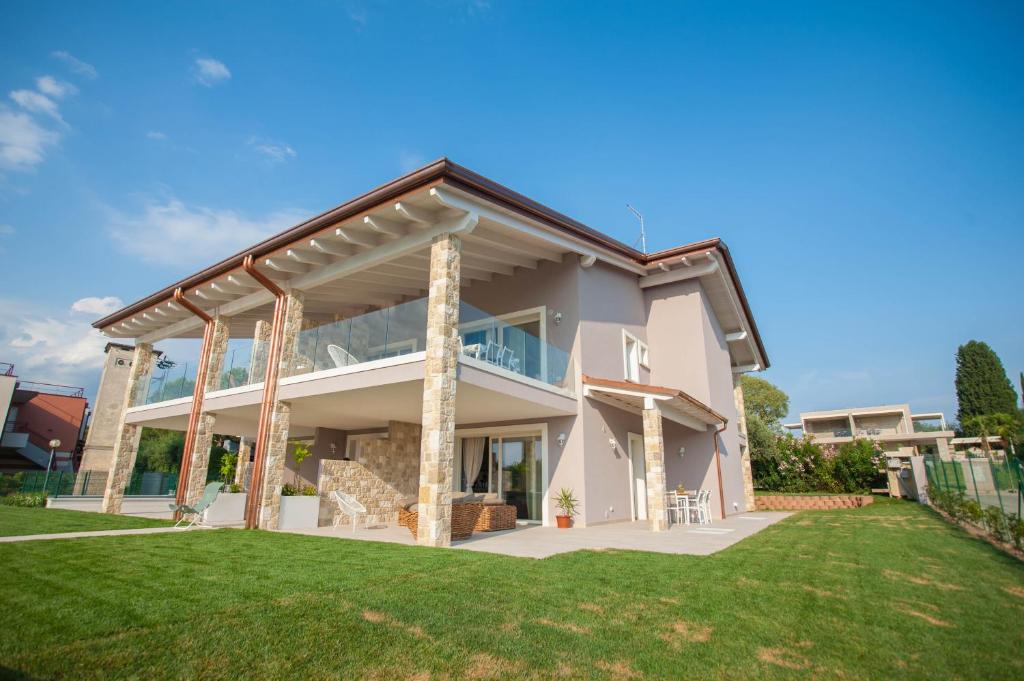 een groot huis met een veranda en groen gras bij Italianflat - Maison du Lac in Lazise