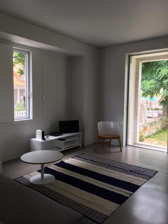 a living room with a desk and a table and a window at Trafaria Garden Beach Houses in Trafaria
